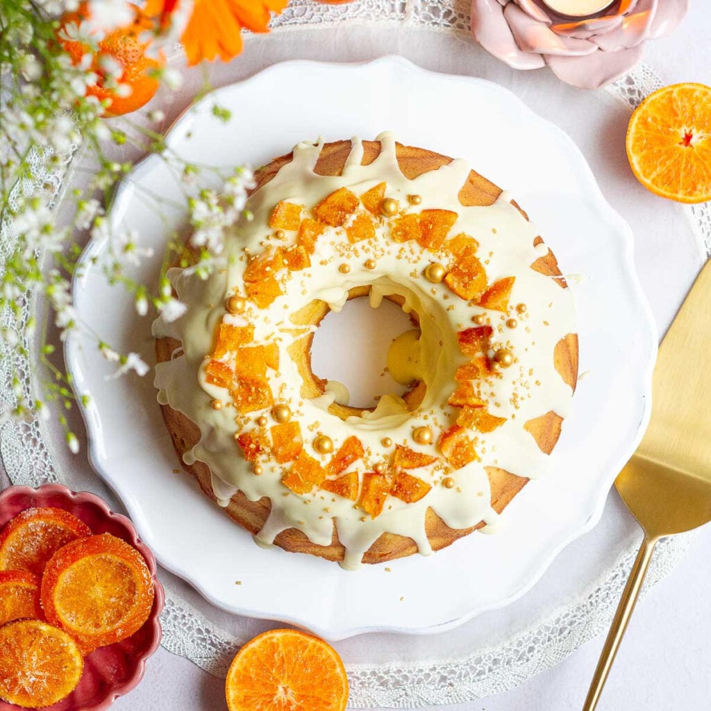 Orange bundt cake on a white serving platter.