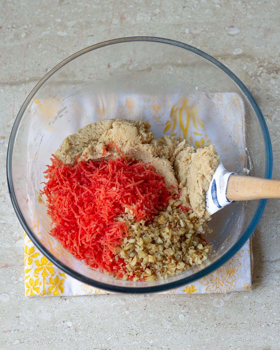 grated carrots and chopped walnuts getting folded in the batter