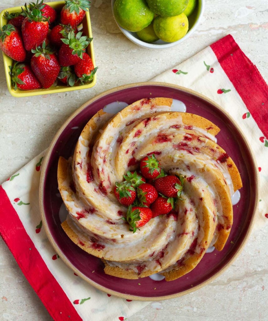 Strawberry Bundt Cake on a red platter with strawberries on the side.