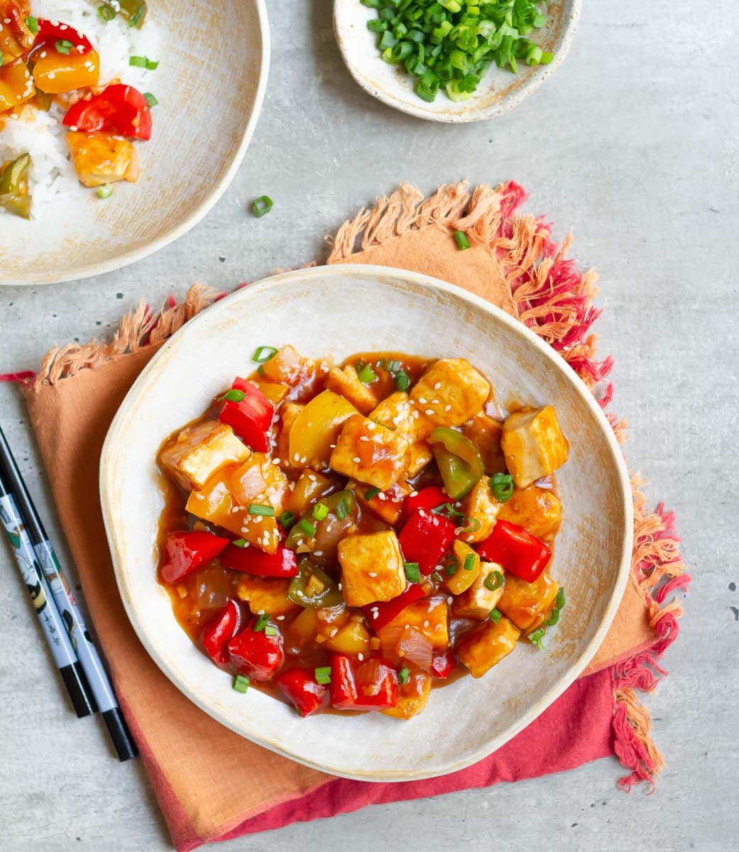 Crispy Tofu With Sweet and Sour Sauce garnished with spring onions and sesame seeds