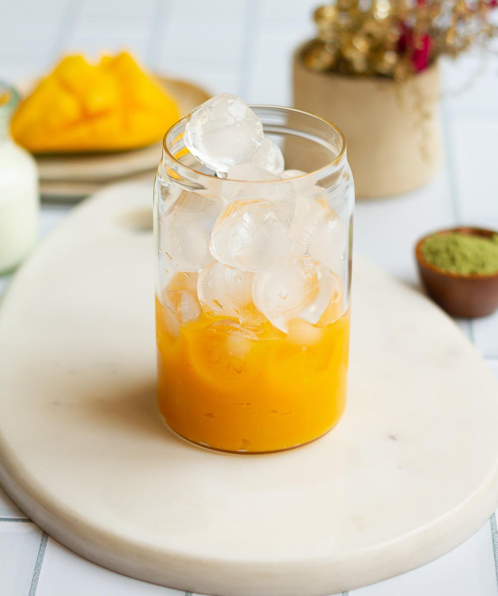 Ice in the glass on top of mango puree.