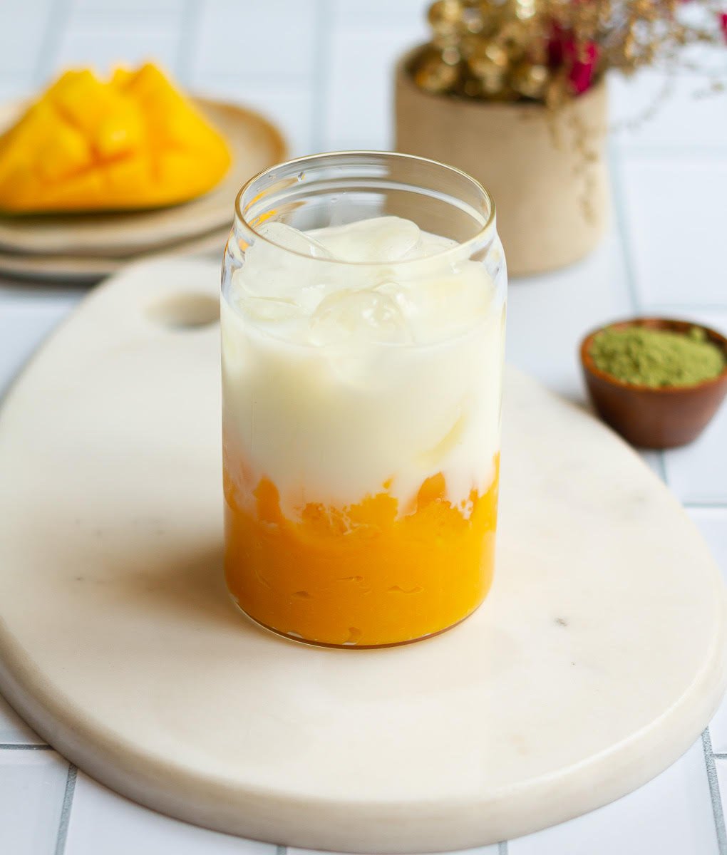Milk on top of the mango puree and ice in the glass.