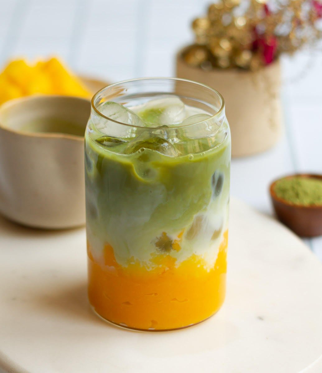 Matcha on top of the milk, ice and mango puree in a glass.