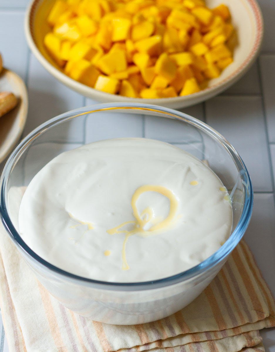 Sweetened condensed milk on top of whipped cream in a bowl.