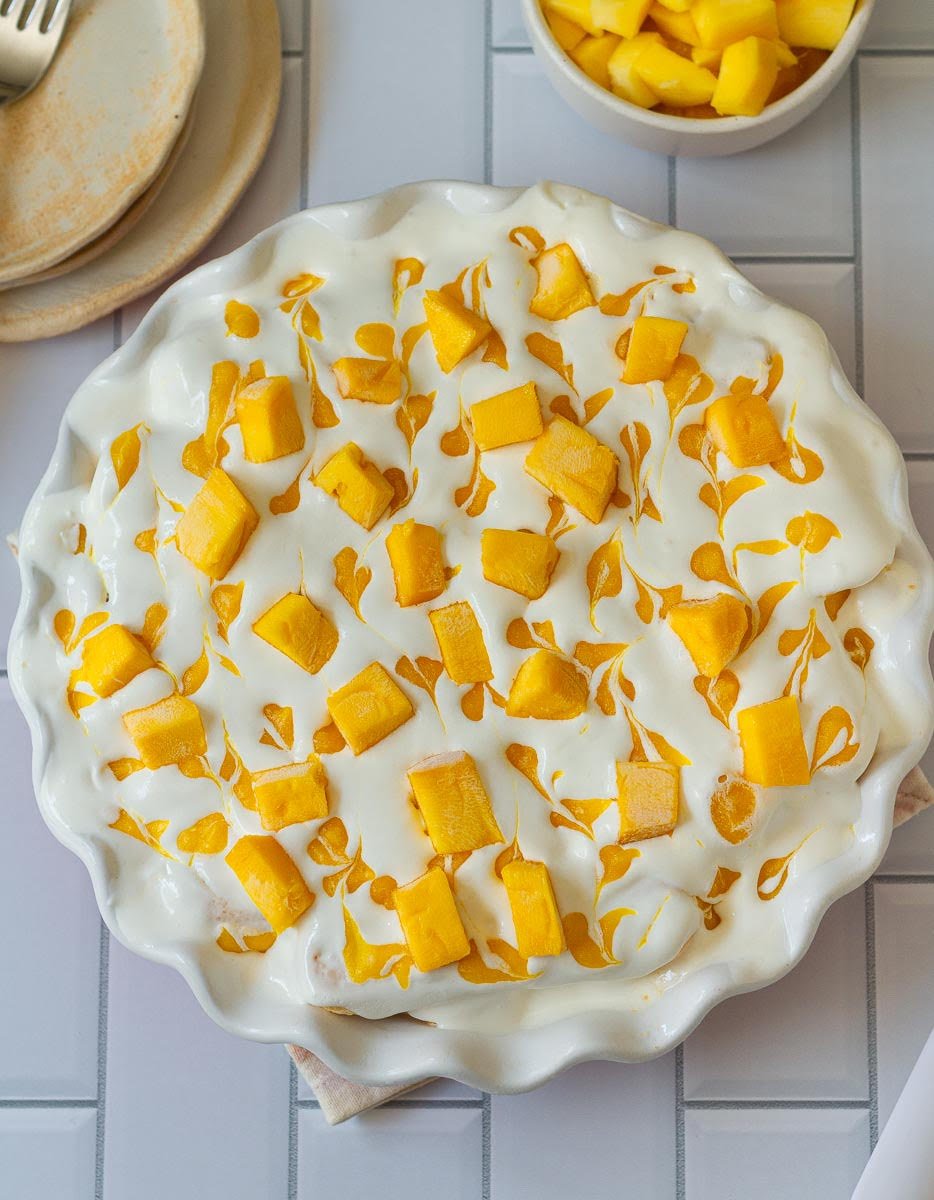 mango float in a serving dish, topped with mango puree and mango cubes.