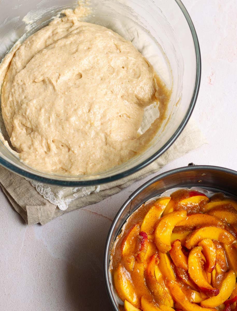 cake batter and cake tin with sliced peaches