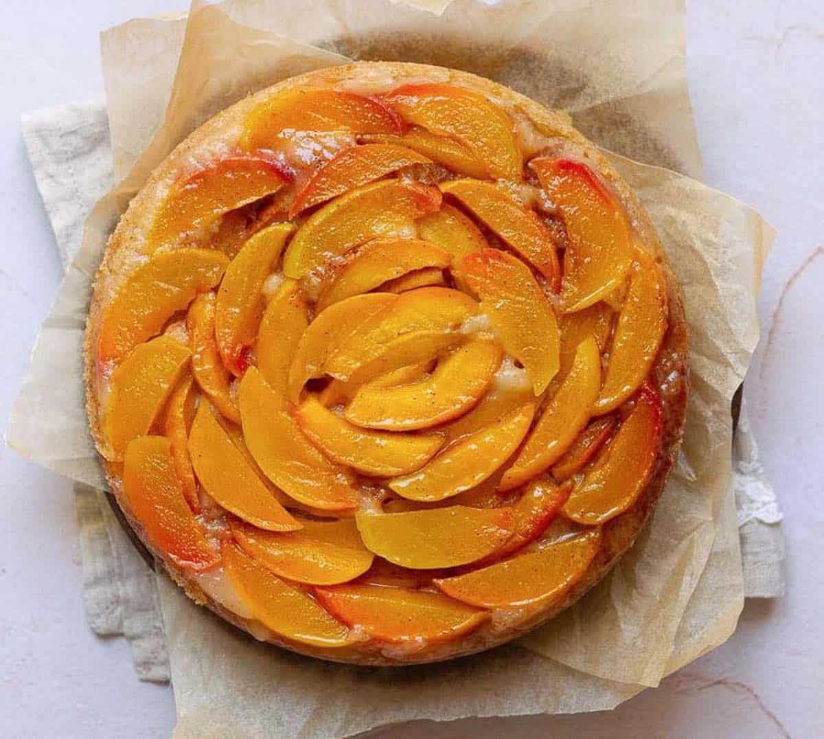 Inverted peach cake on parchment paper.