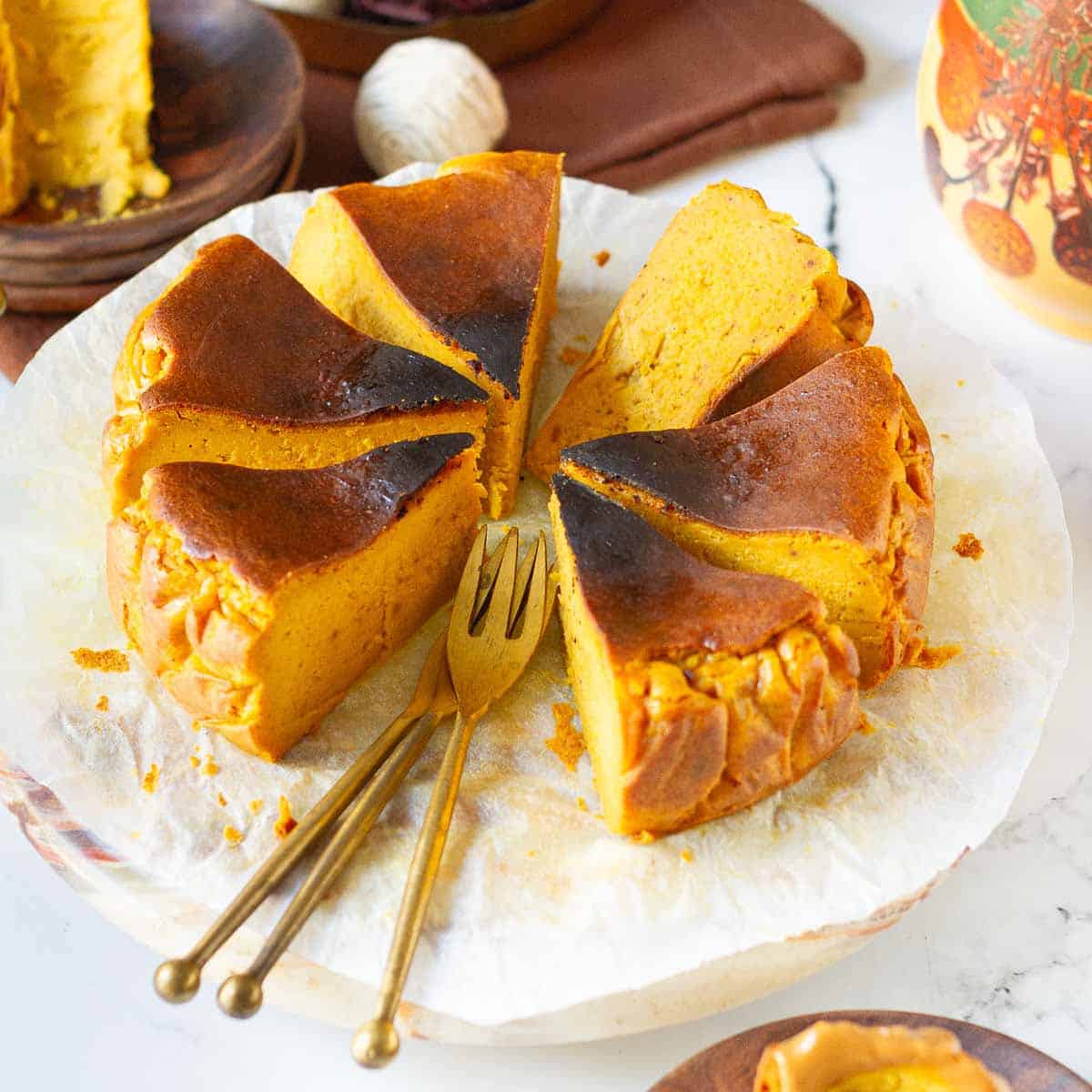 Sliced pumpkin cheesecake on parchment paper with 2 forks.