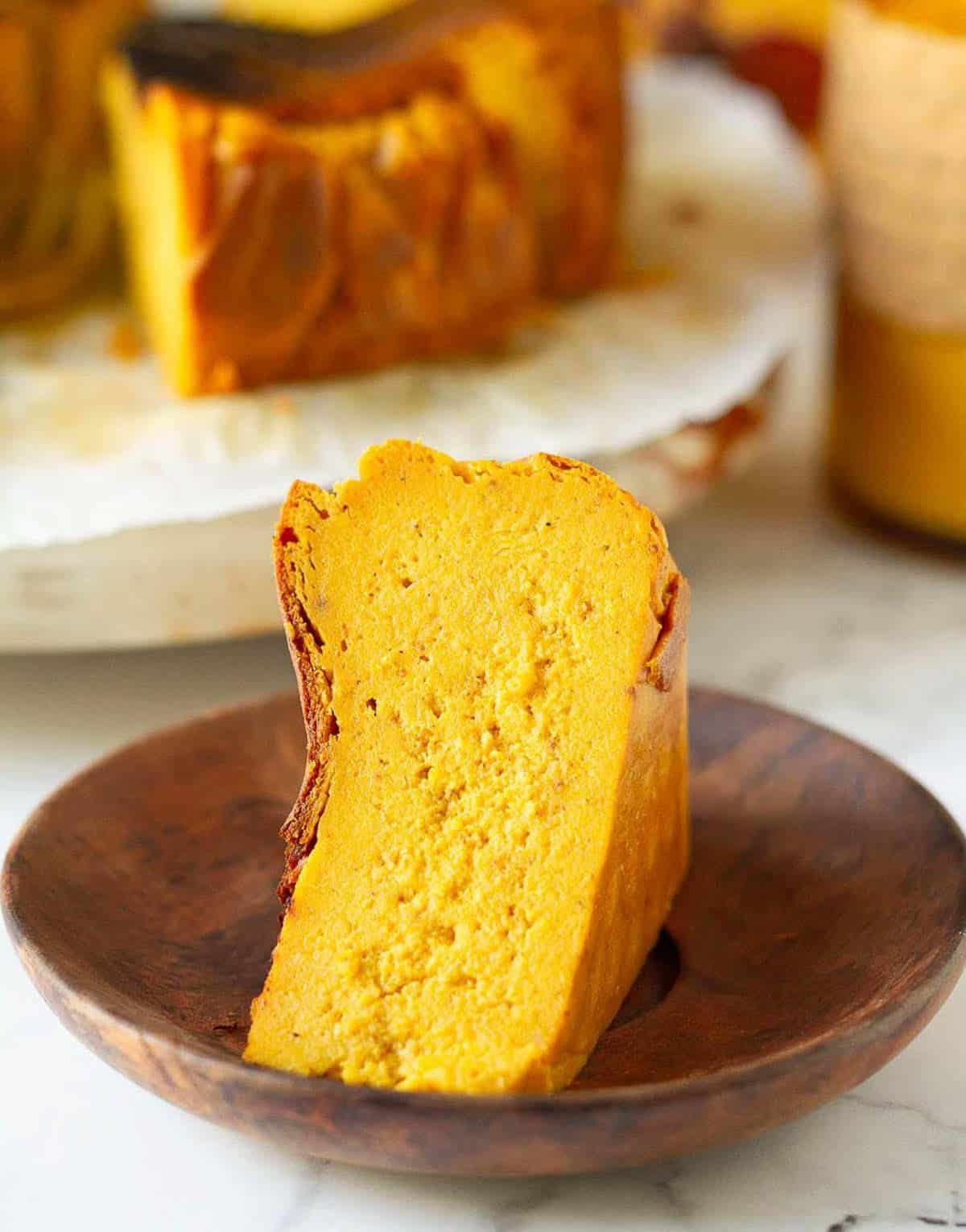 A slice of cheesecake on a small wooden plate.