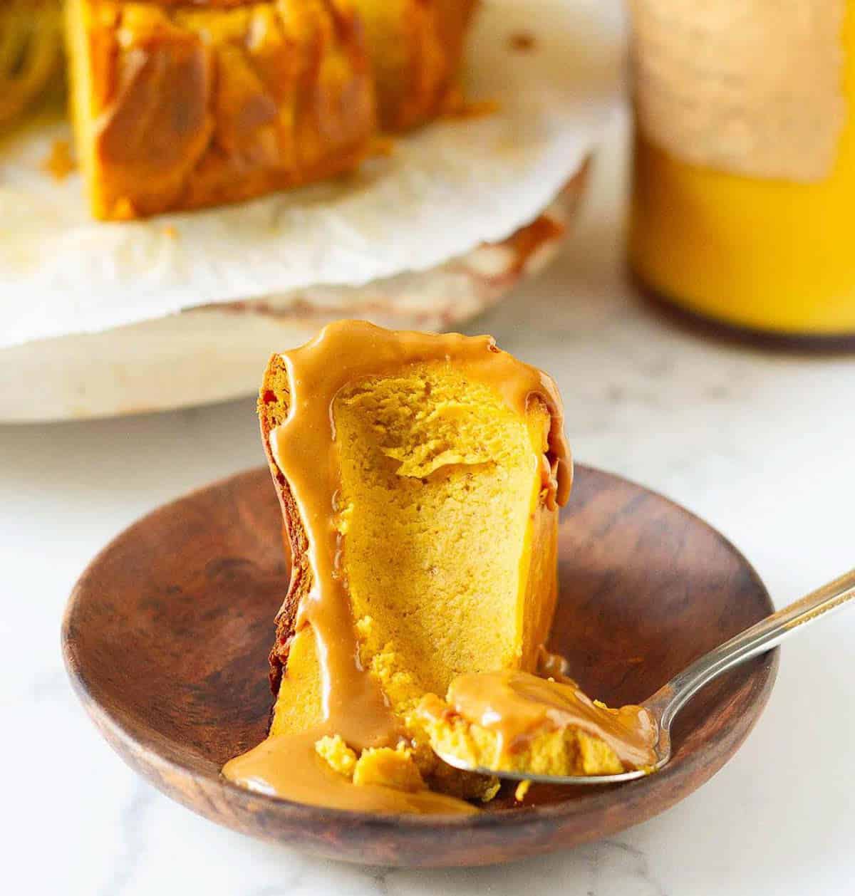 A slice of pumpkin cheesecake with Biscoff on a small plate with a bite taken.