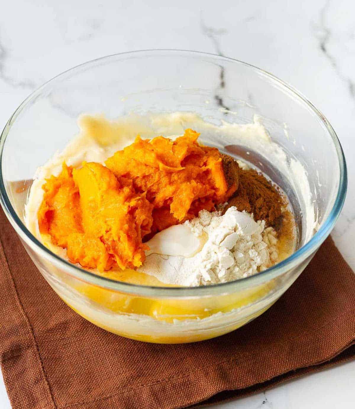pumpkin puree, flour, eggs, cream cheese, pumpkin spice and sugar in a mixing bowl.