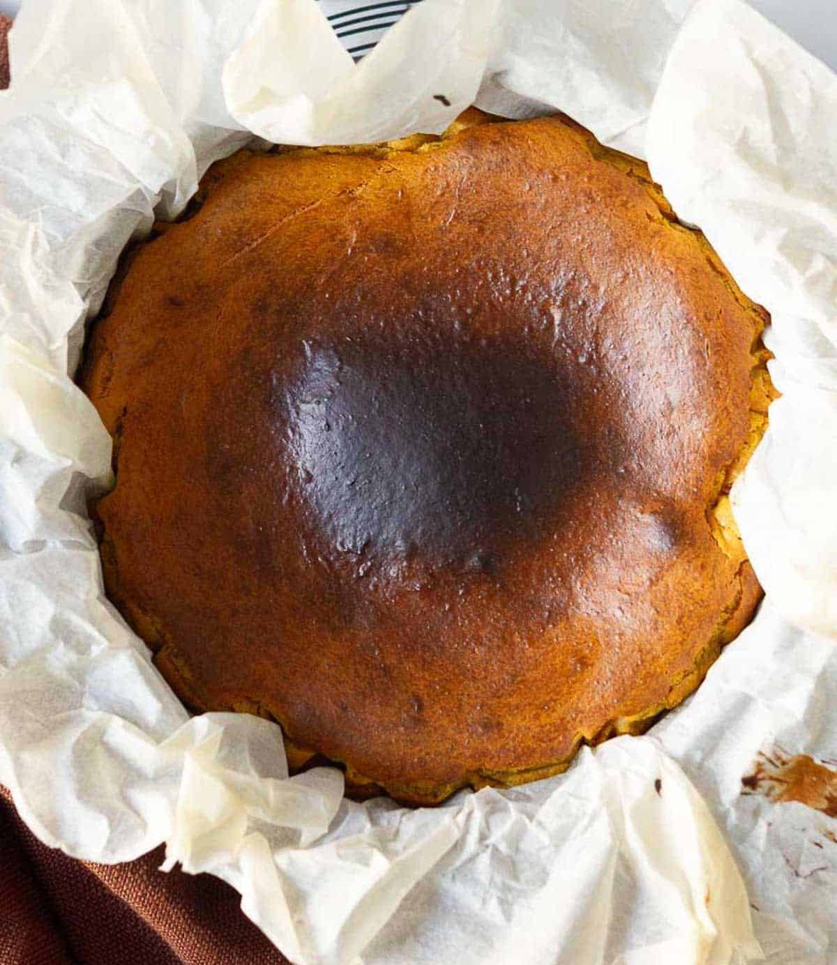 baked pumpkin cheesecake in a parchment lined cake pan.