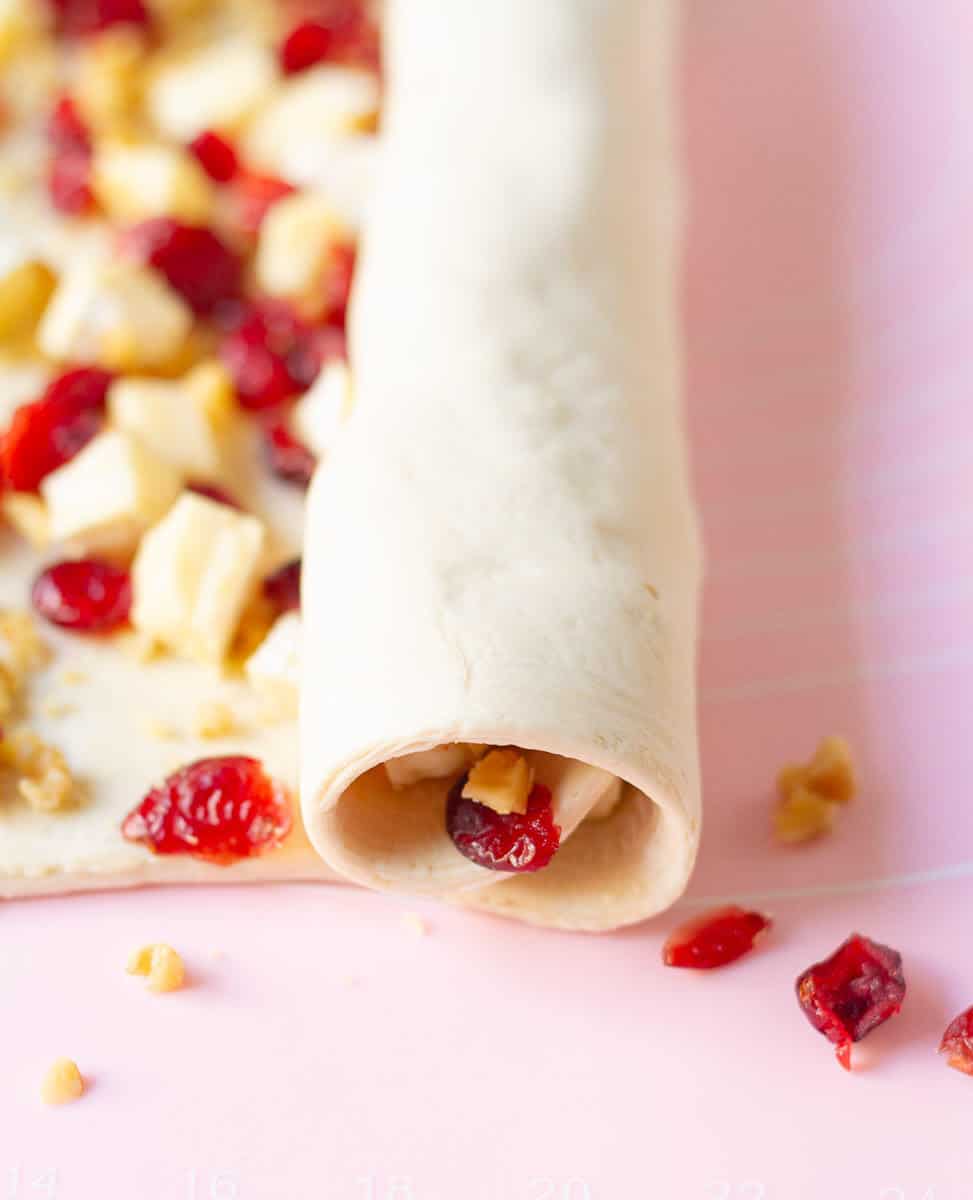 puff pastry with the cheese and cranberry filling getting rolled into a tight log.
