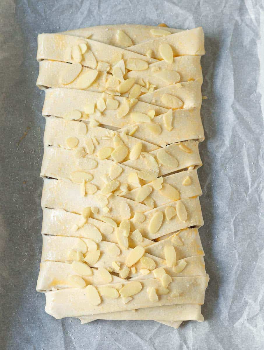 Pastry braid brushed with egg and topped with almond flakes and granulated sugar