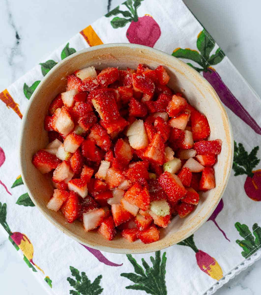 Strawberries mixed with sugar in a bowl.