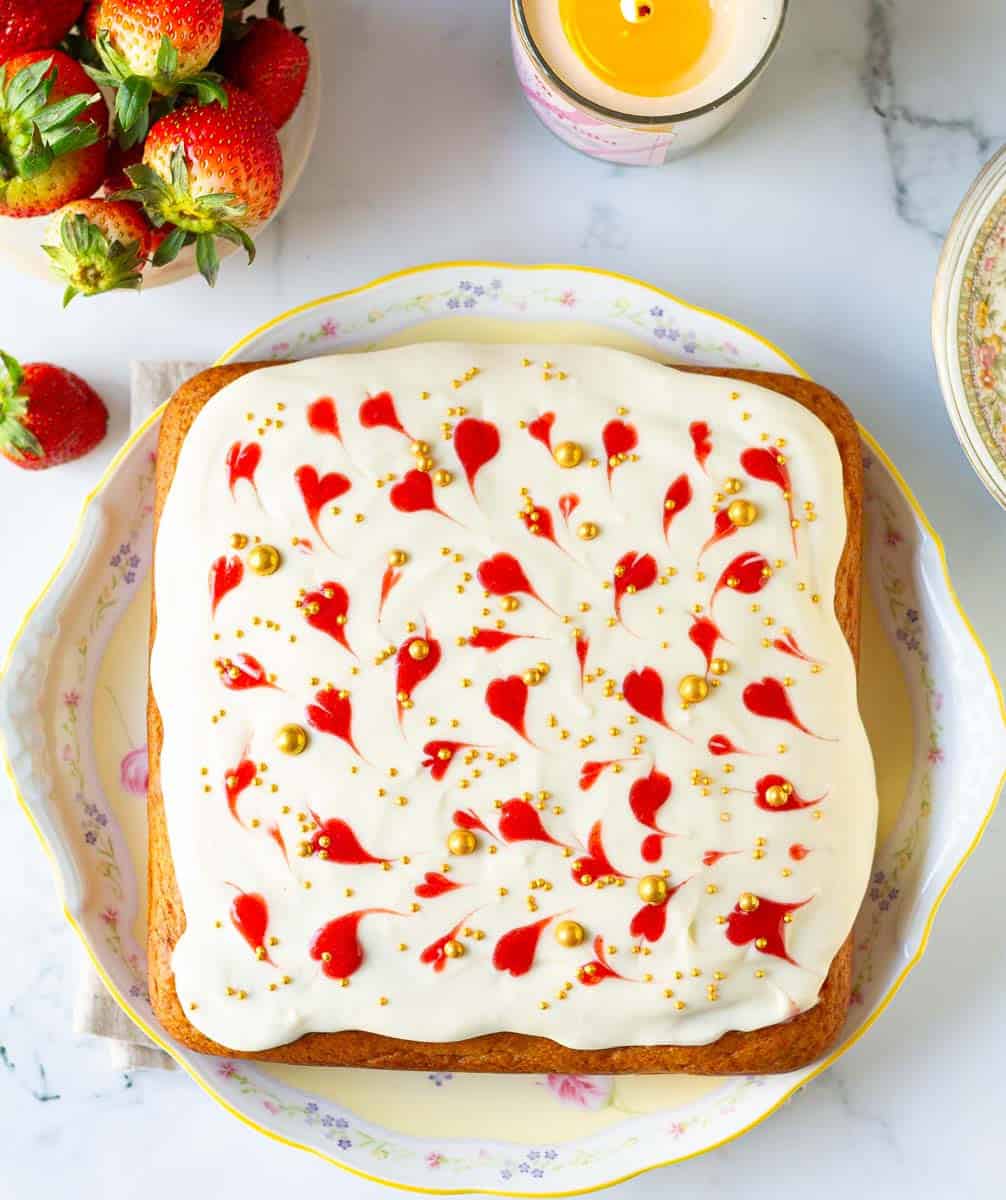 Fresh Strawberry Poke Cake with mascarpone frosting and golden dragees.