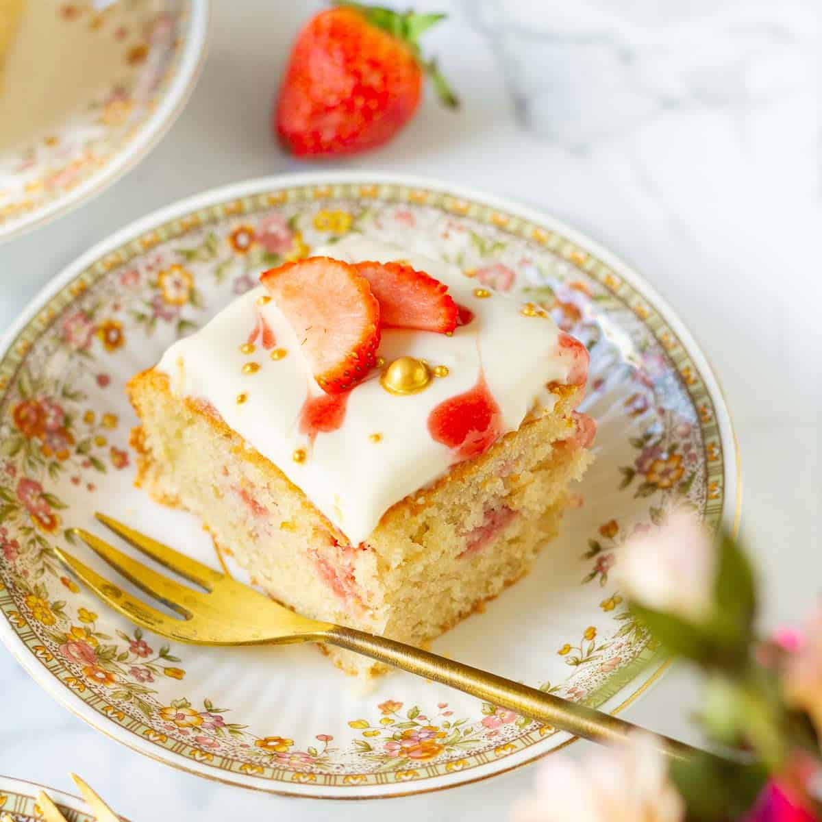 a slice of strawberry poke cake on a small plate with a fork.