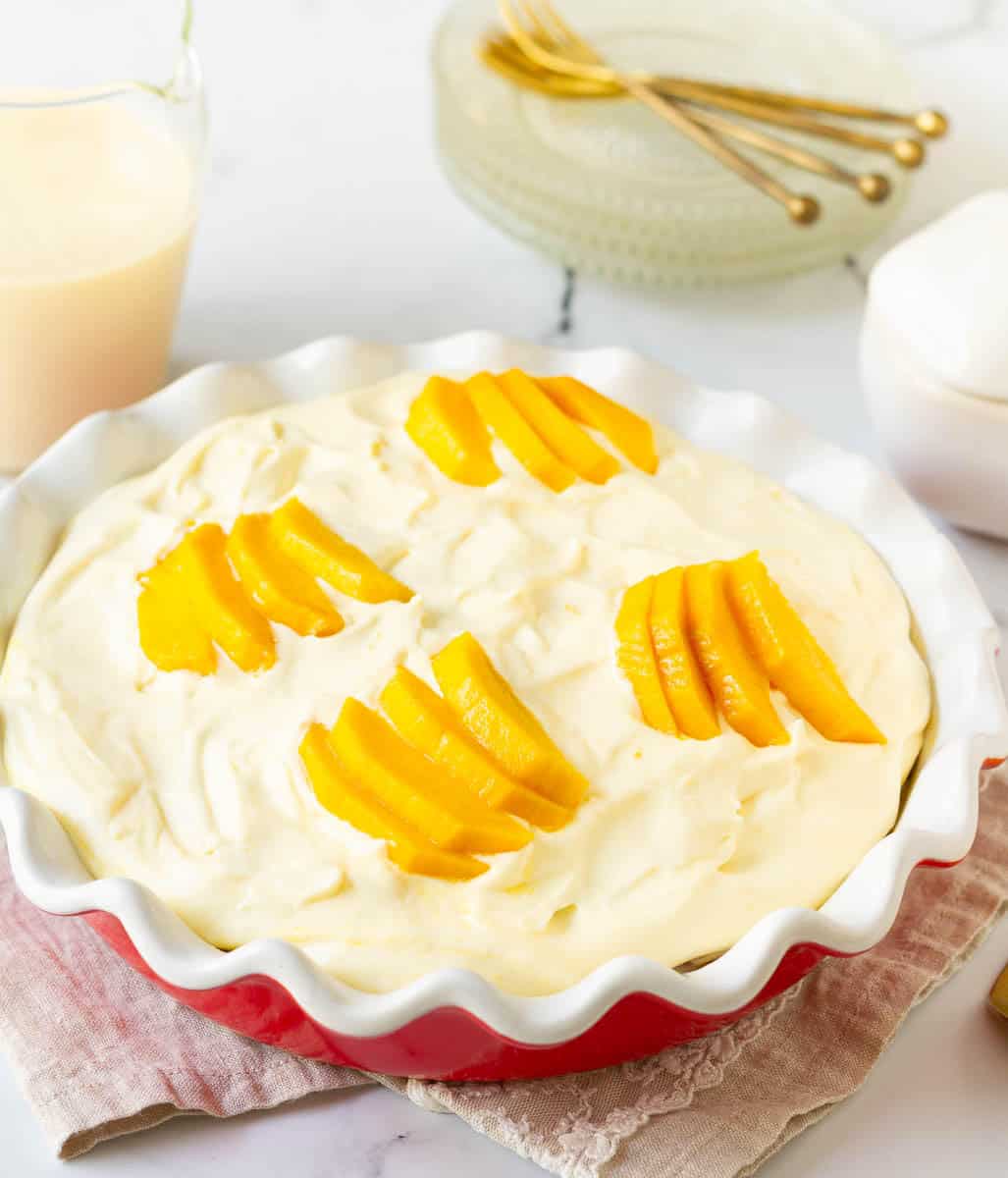 Cake topped with whipped cream and mango slices.