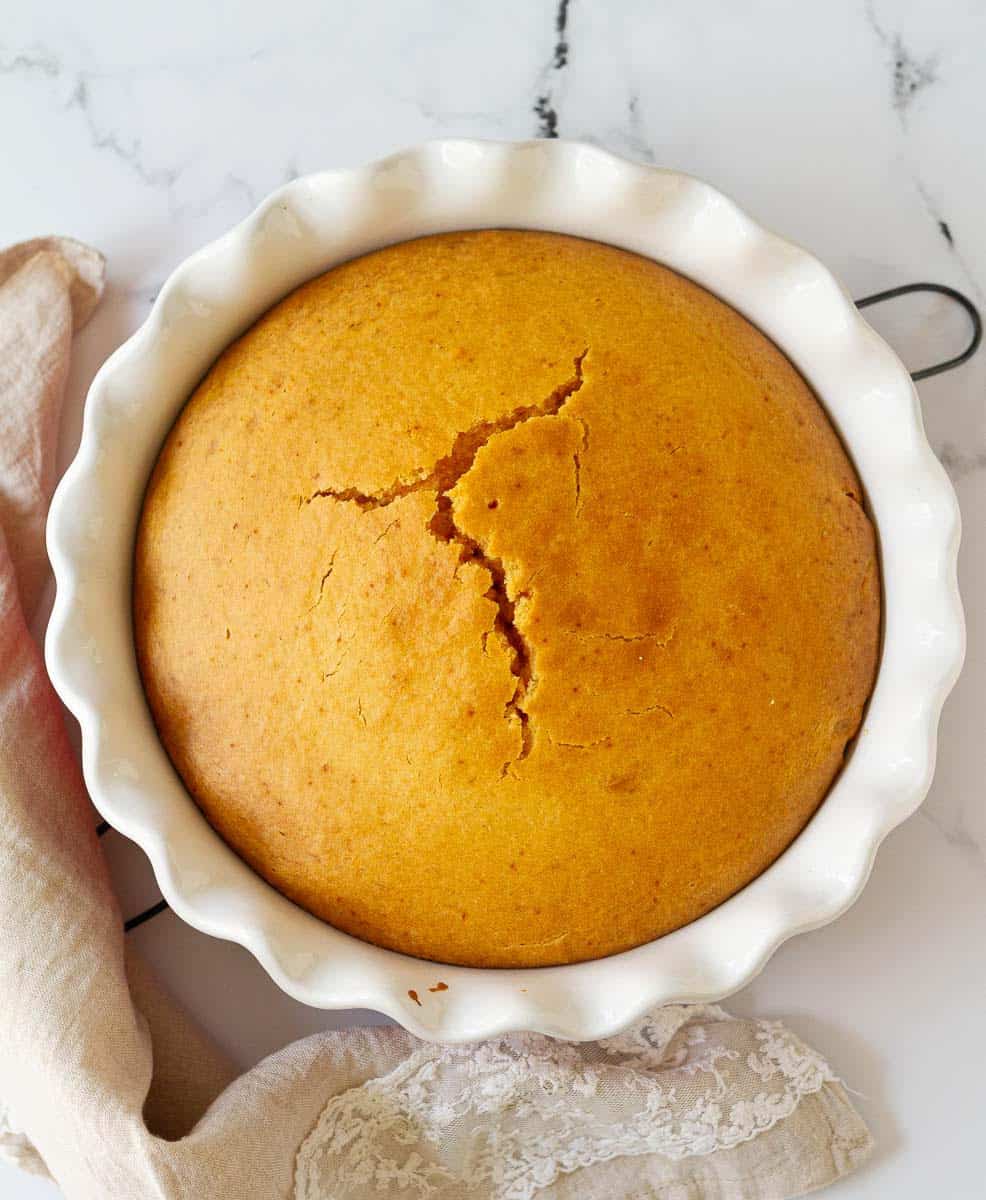 baked mango cake in a round cake dish.