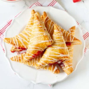 strawberry turnovers on a white plate on a cloth napkin.