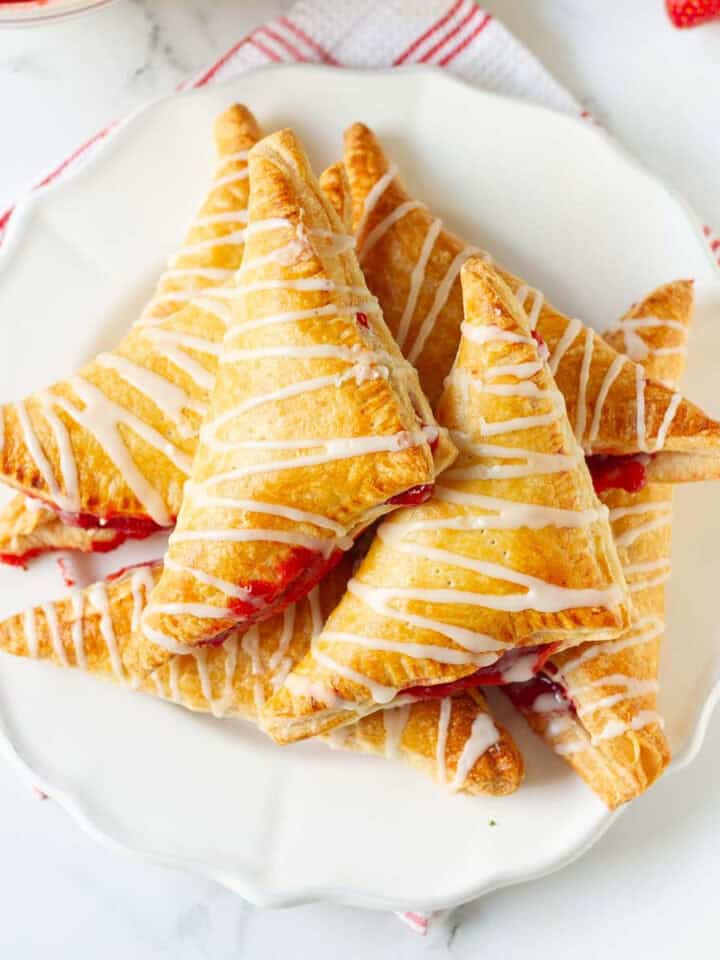 strawberry turnovers on a white plate on a cloth napkin.