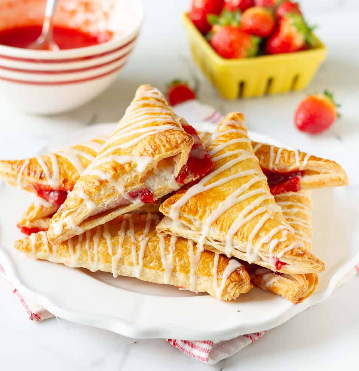 strawberry turnovers on a white plate with ingredients in the background.