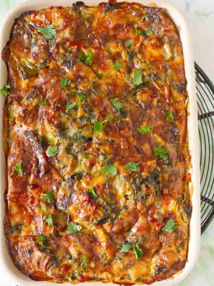 breakfast casserole with eggs and veggies in a baking dish on a metal trivet.