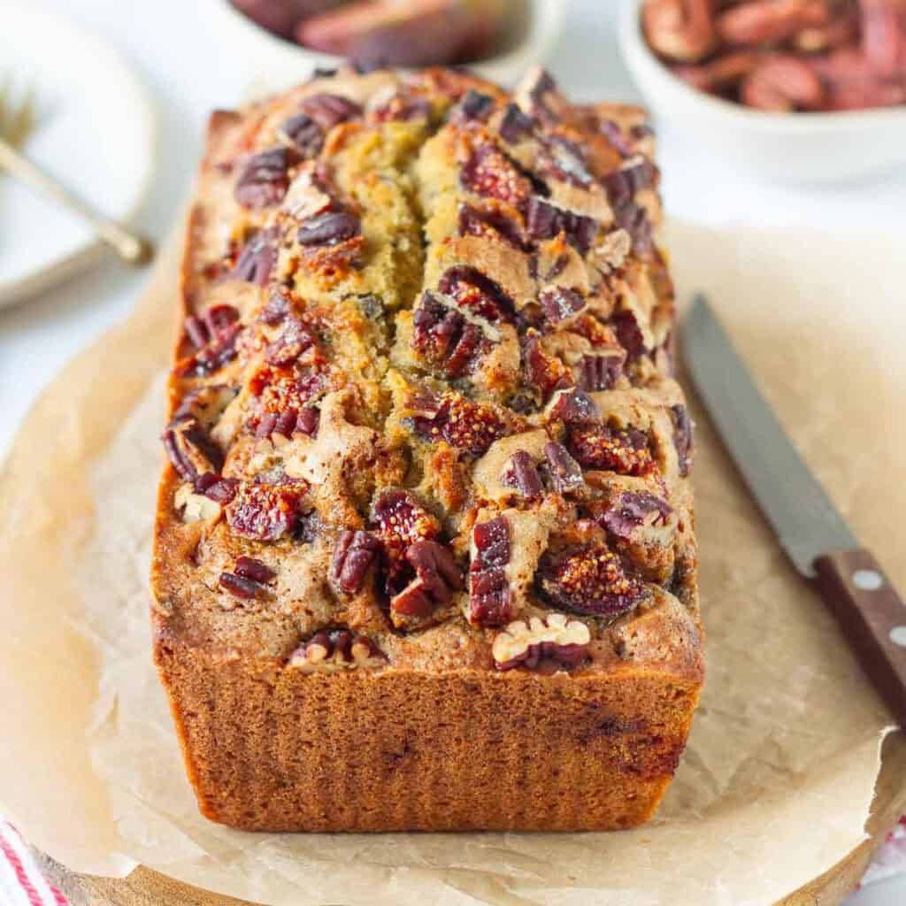 Fig bread on parchment paper with a knife on the side.