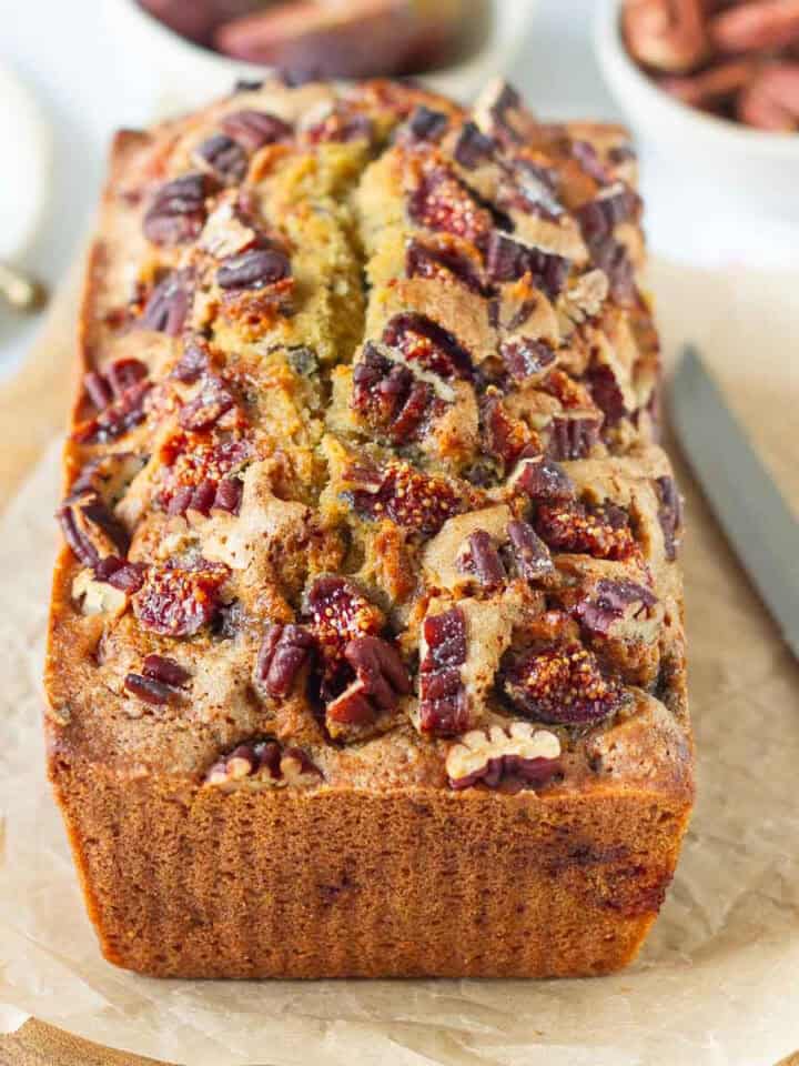 Fig bread on parchment paper with a knife on the side.