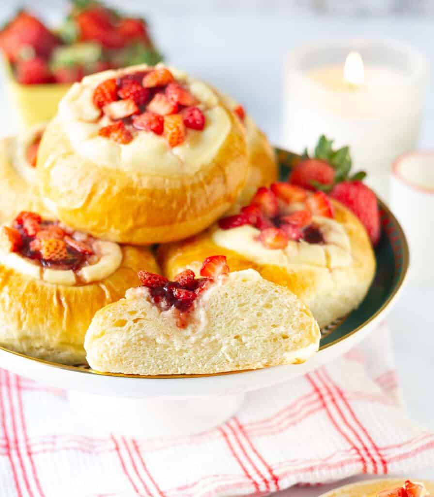 strawberry rolls on a cake stand with one roll cut in half to show the texture.
