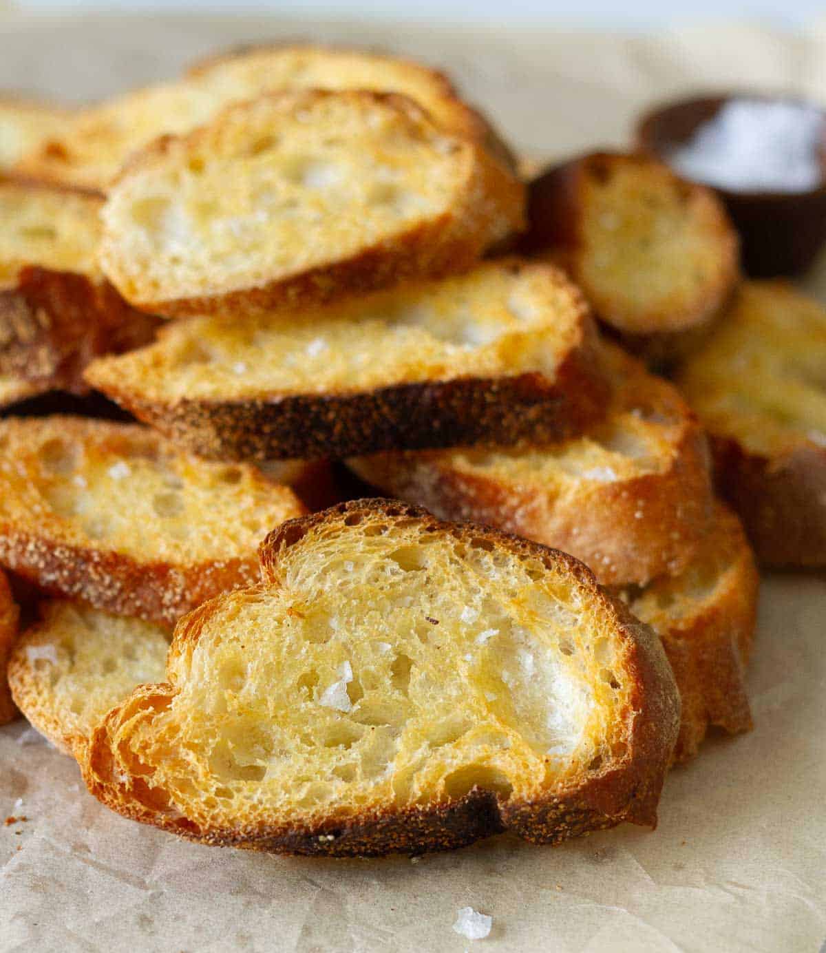 Crostini piled on top of each other on parchment paper.