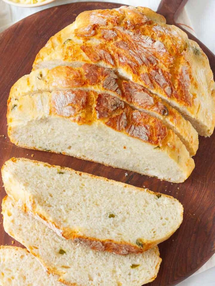 Sliced loaf of jalapeño cheddar bread on a wooden board.