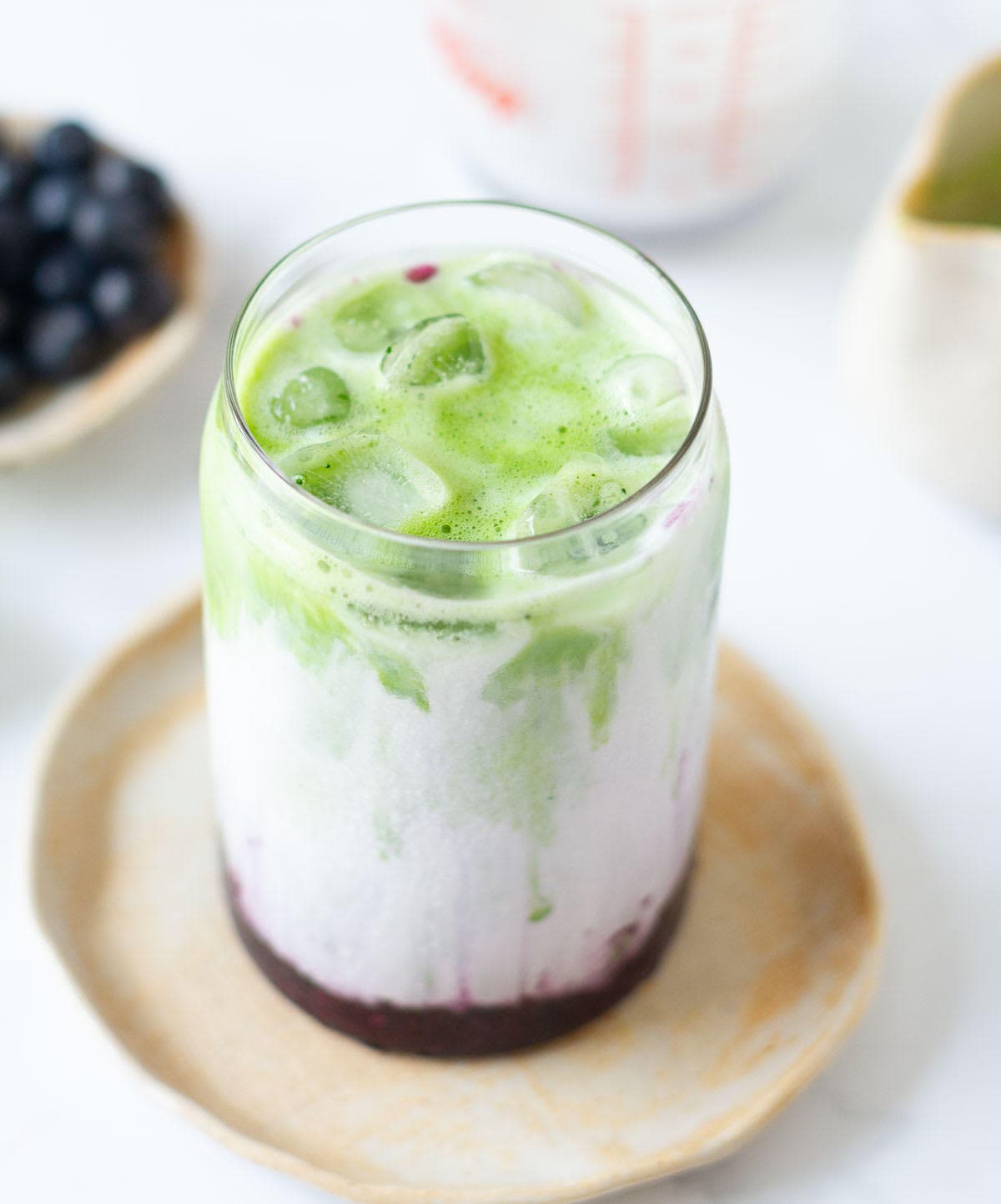 Matcha mixture on milk, and blueberry syrup in a glass.