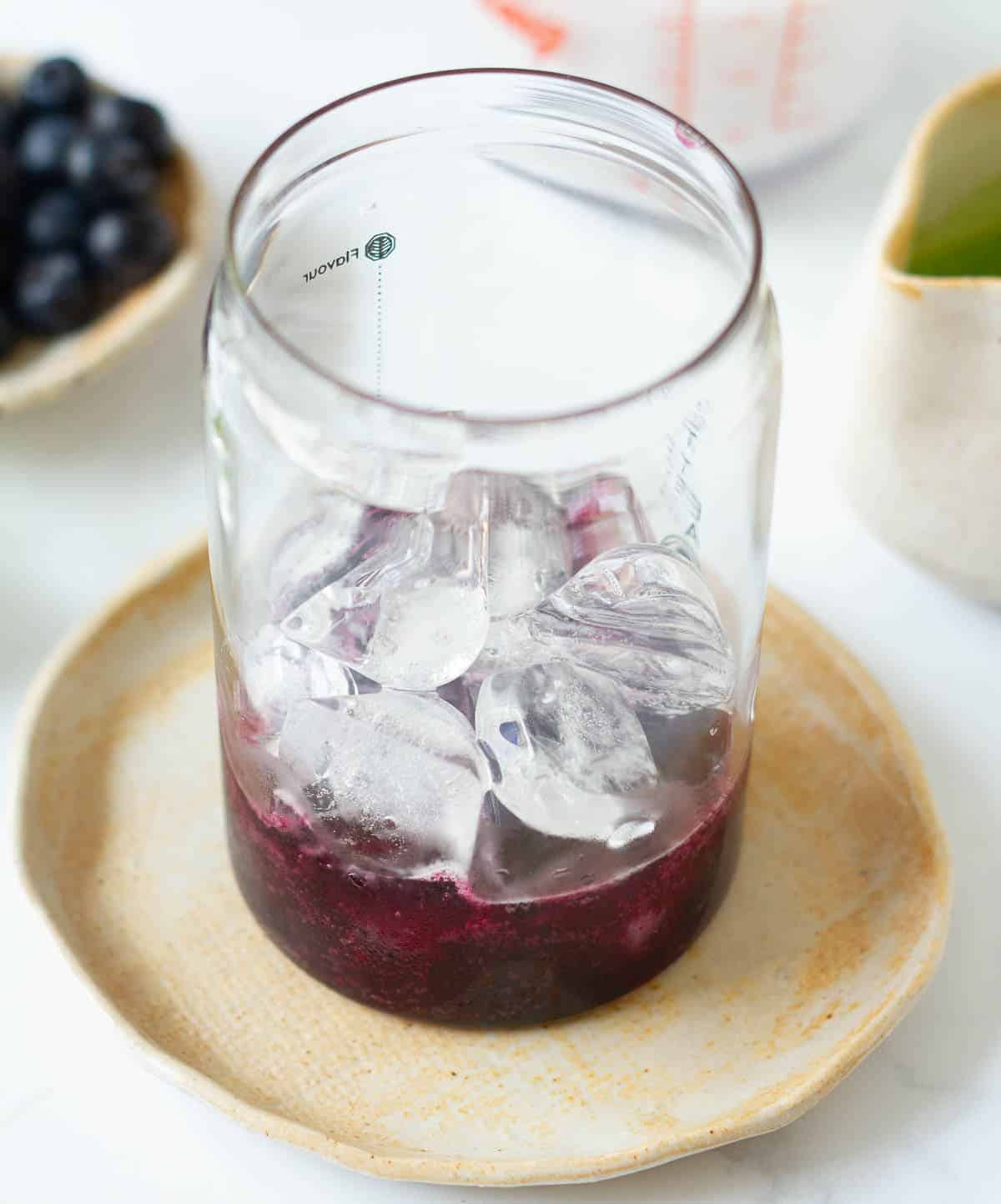 Blueberry syrup with ice in a glass.