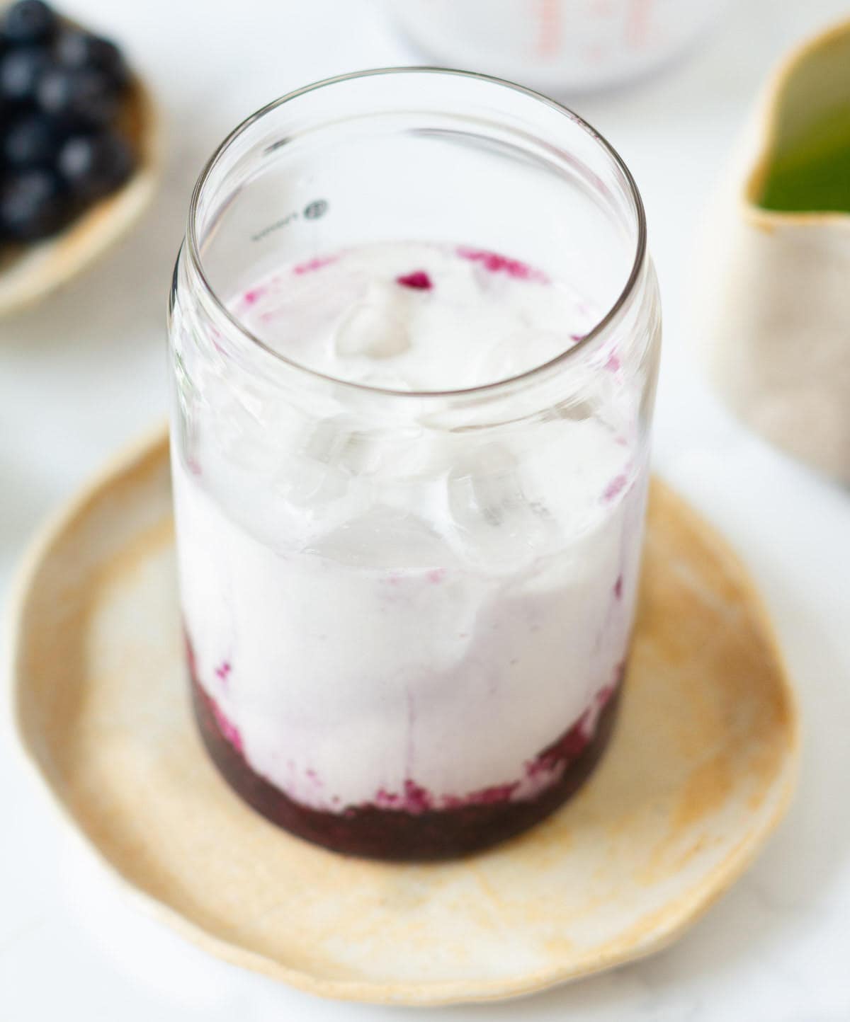 Milk on top of ice and blueberry syrup in a glass.