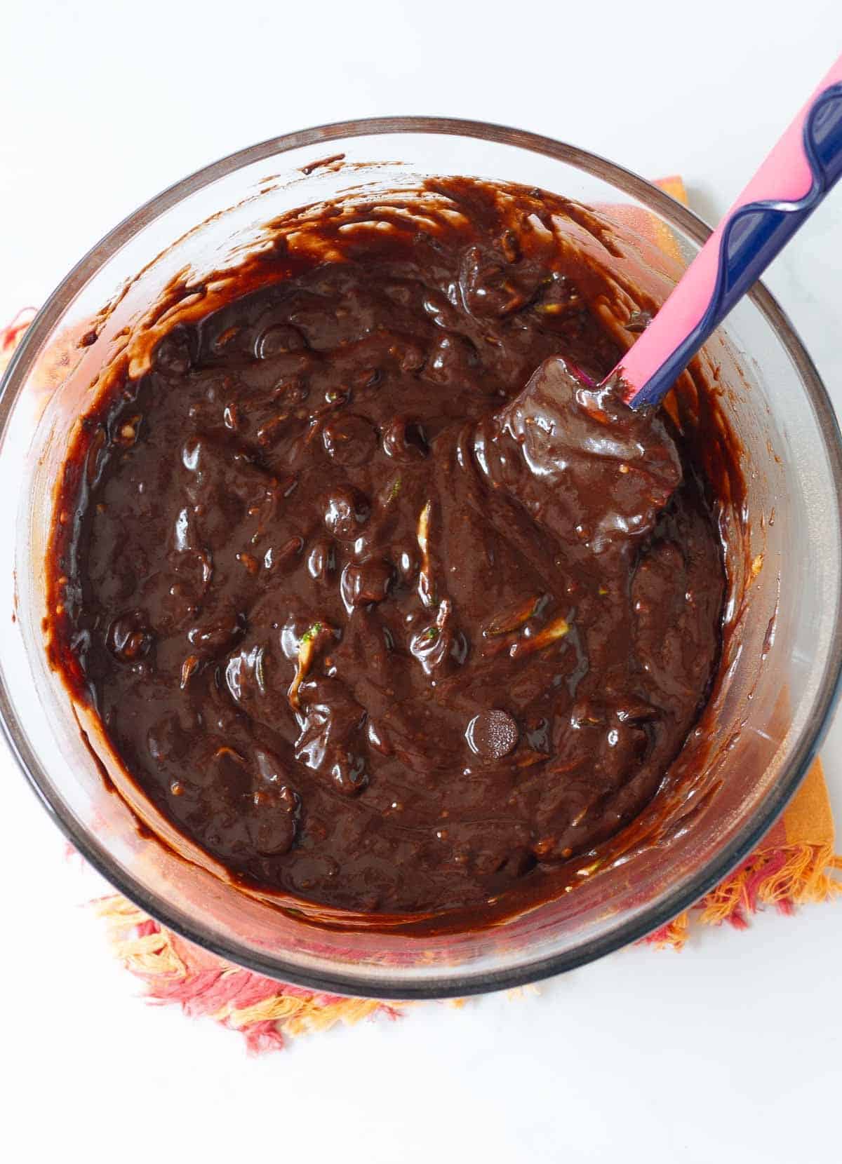 Chocolate cake batter with a spatula in a mixing bowl.
