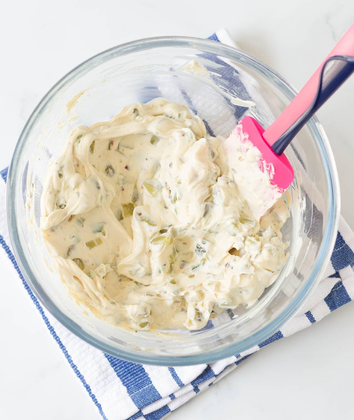 Cream cheese pickle dip in a mixing bowl with a pink spatula.