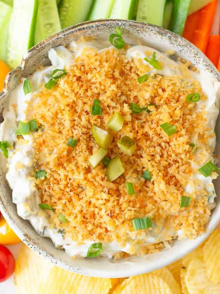 Fried pickle dip in a serving bowl with veggies and chips around.