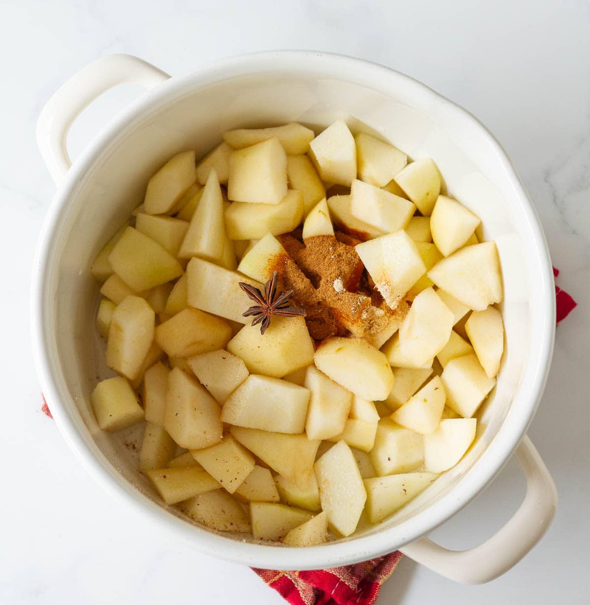 Chopped pears, spices, and star anise in a white stock pot.