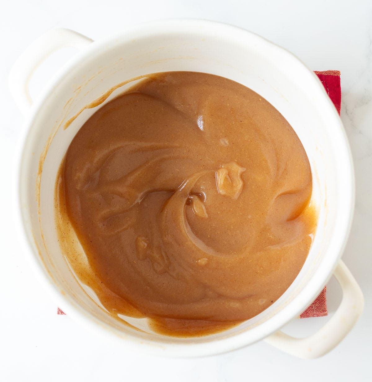 Cooked pear butter in a white stock pot.