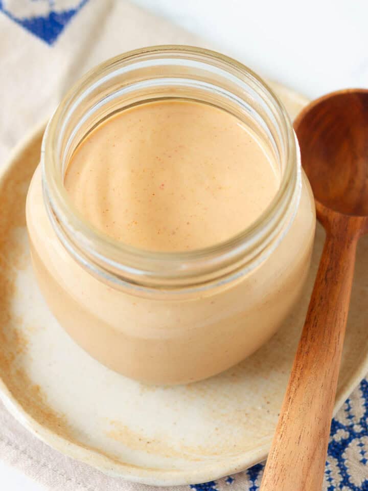 Yum yum sauce in a jar with a wooden spoon on the side.