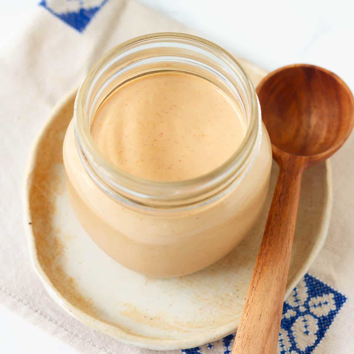 Yum yum sauce in a jar with a wooden spoon on the side.