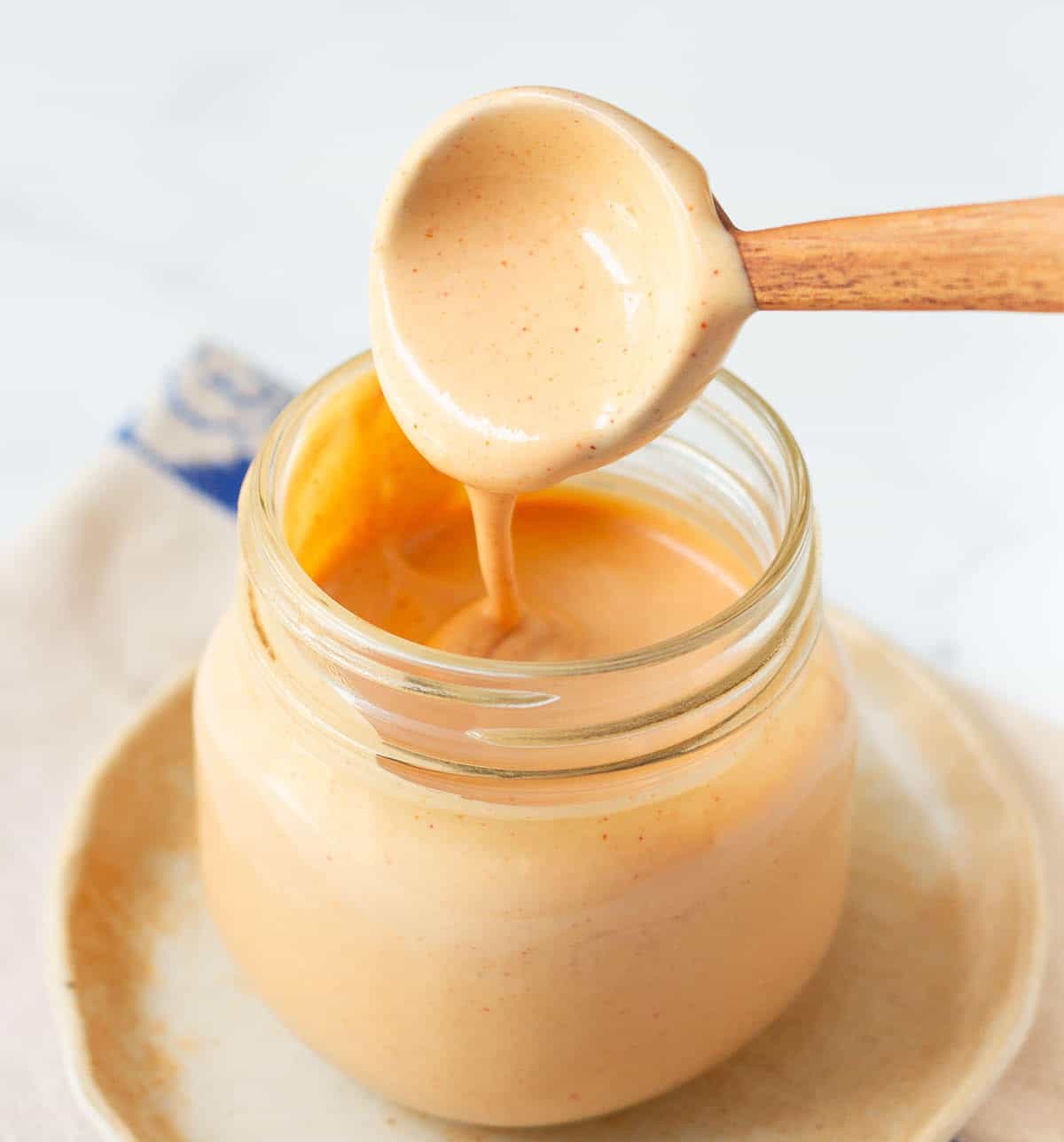 Wooden spoon in a jar of sauce.
