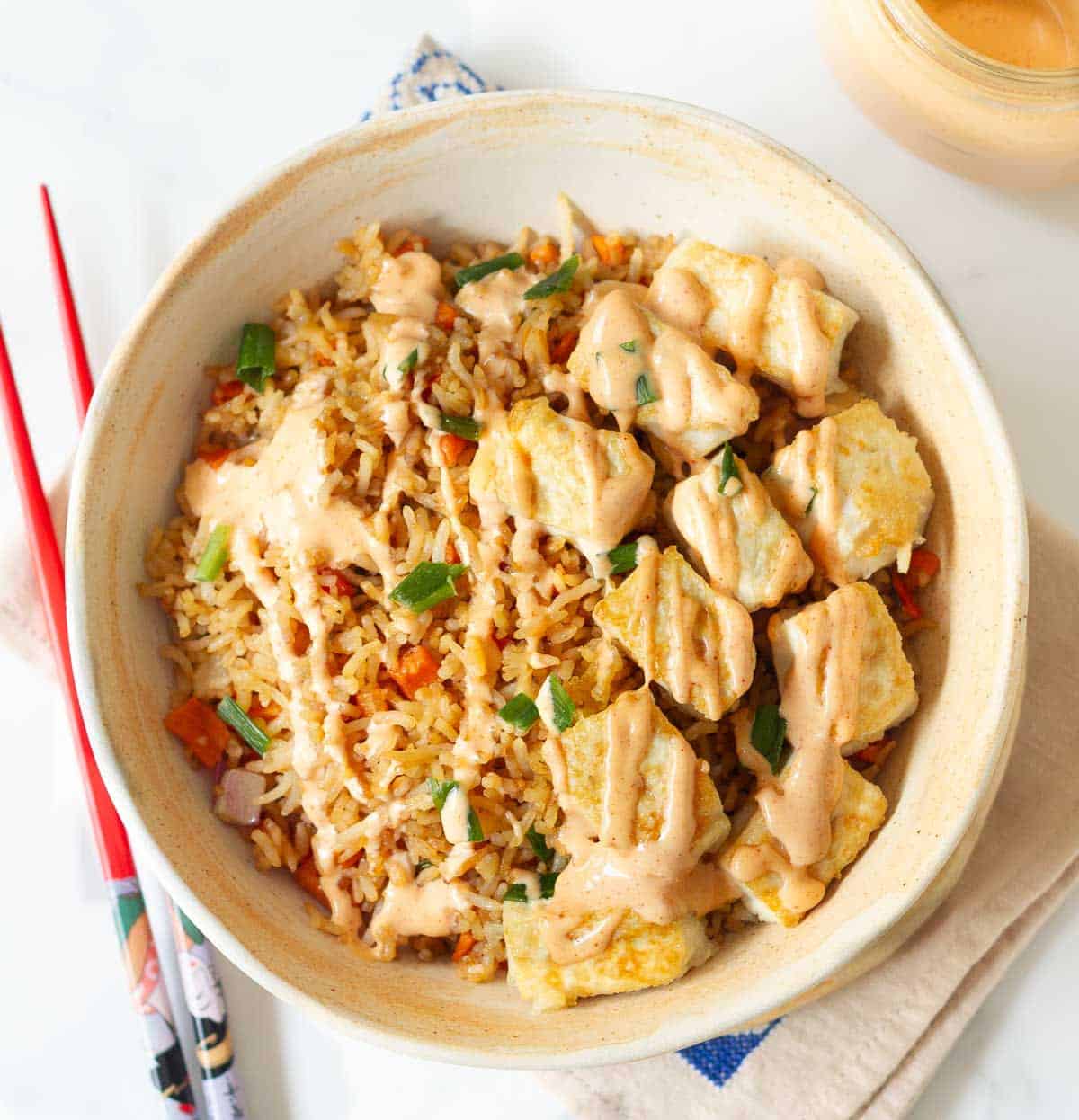 Sauce drizzled over a bowl of tofu fried rice.