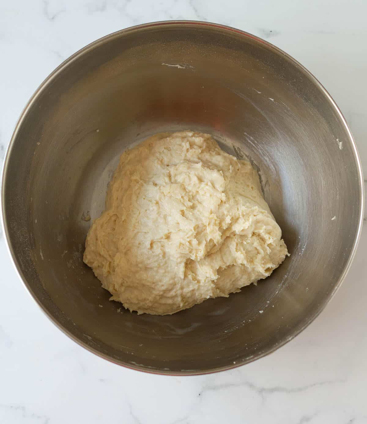 Dough in a stainless steel mixing bowl.