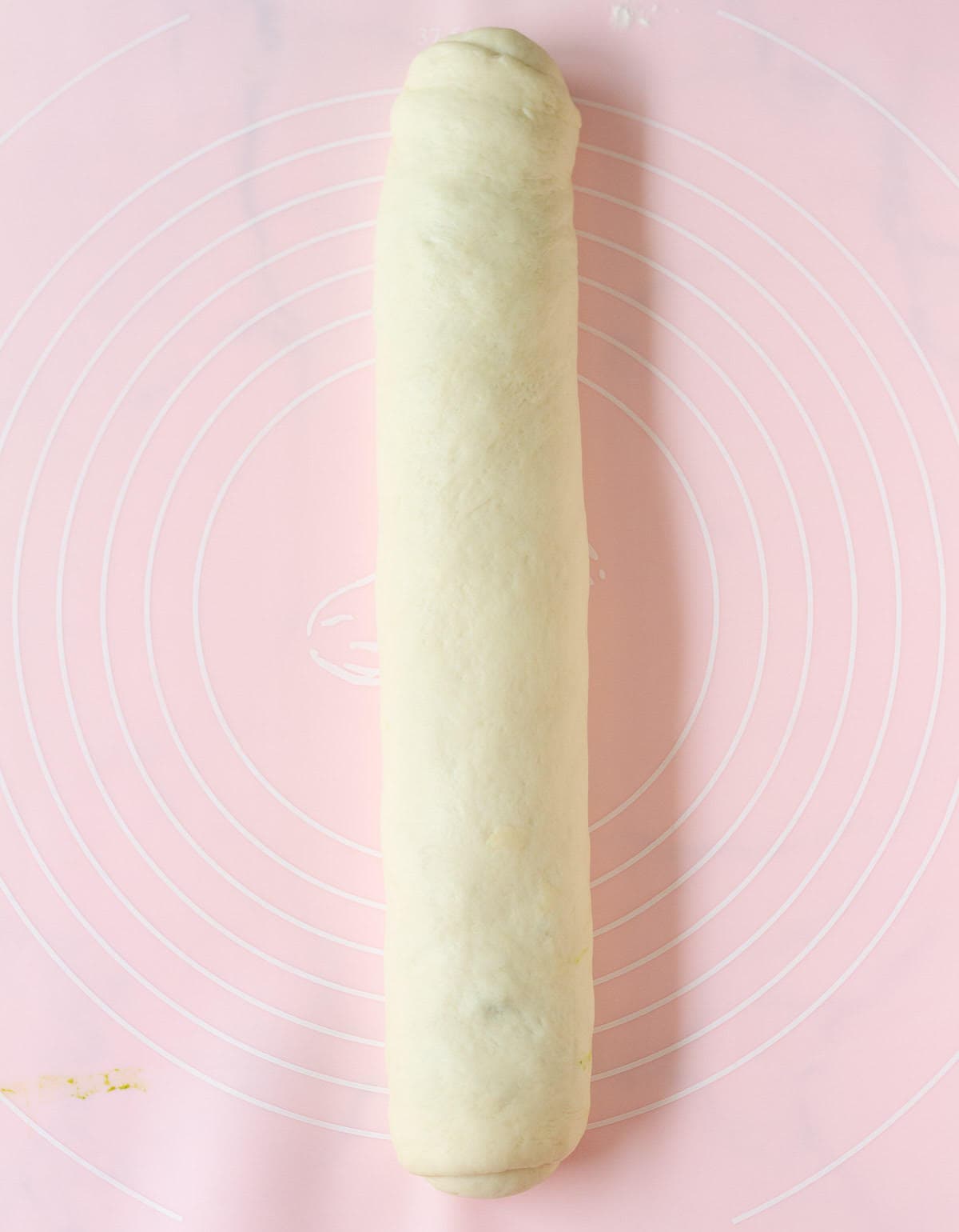 Dough rolled into a log on a pink silicone mat.