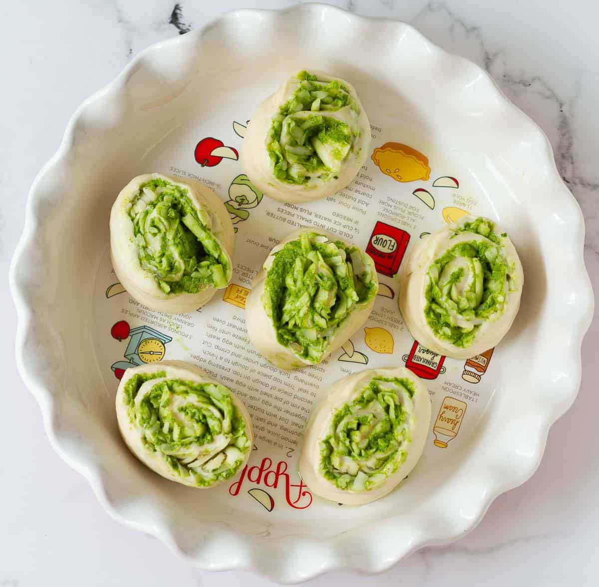 6 pieces of pesto swirled dough on a round pie dish.
