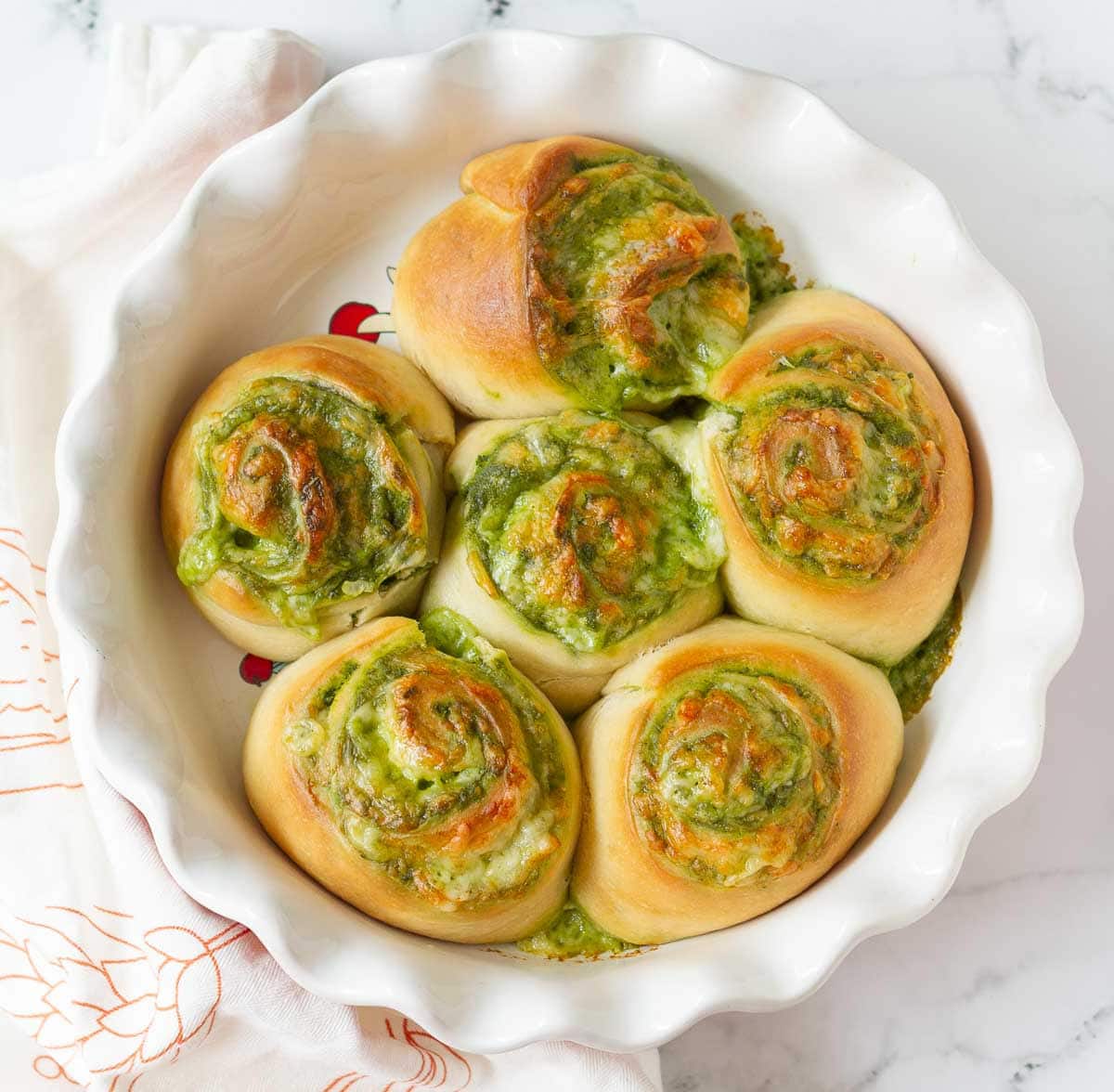 Baked pesto rolls in a round pie baking dish.