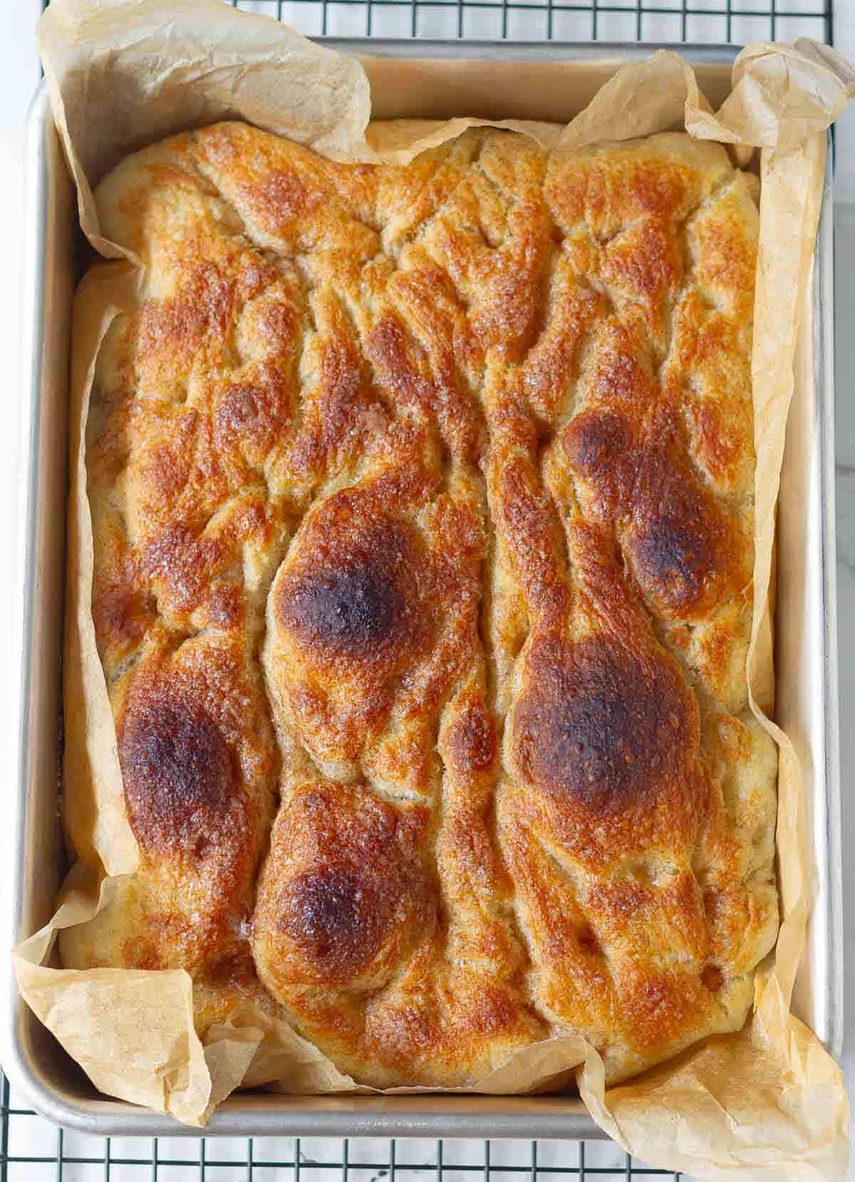 Baked cinnamon focaccia in a baking pan.