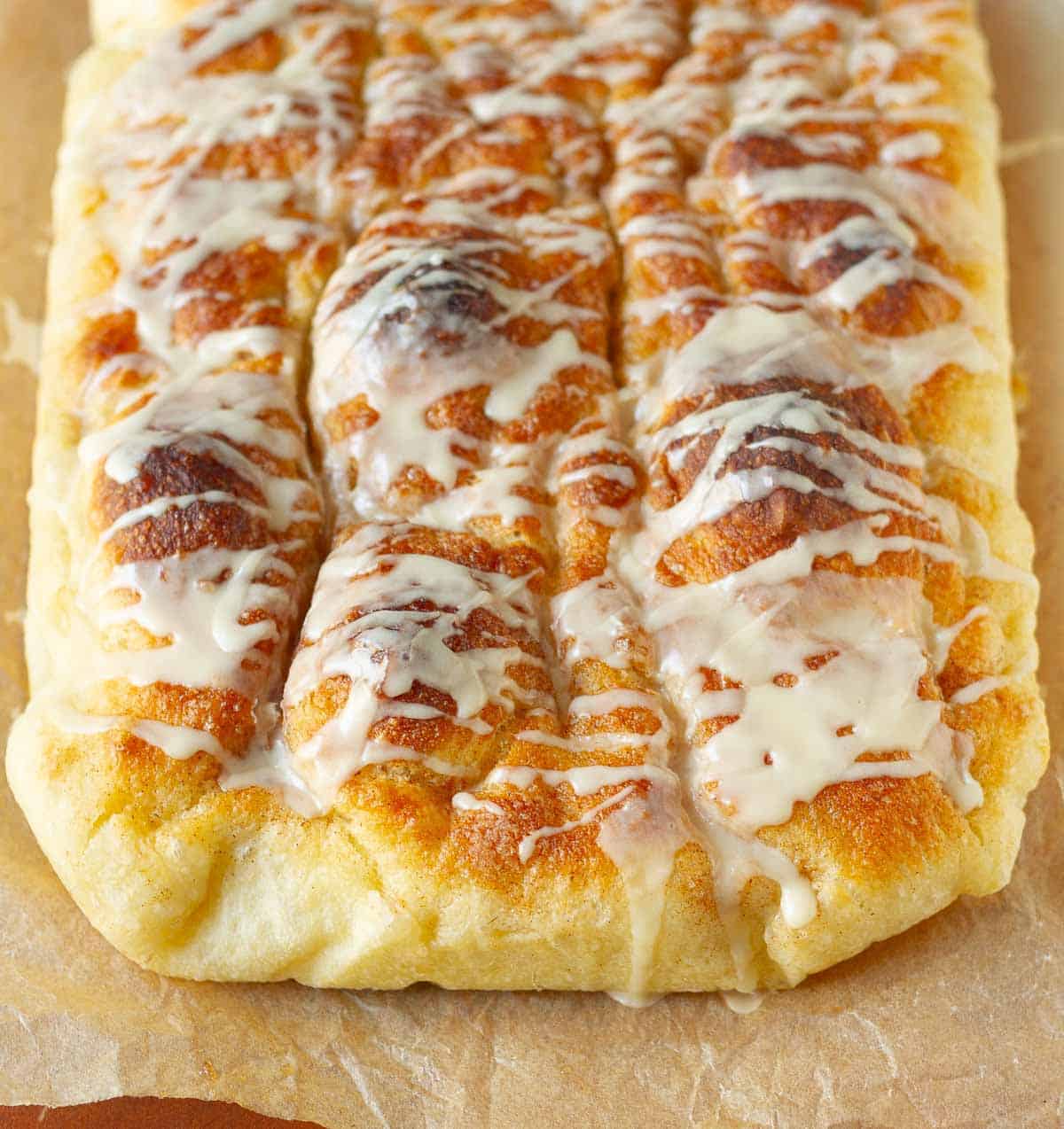 Cinnamon focaccia with vanilla glaze on parchment paper.